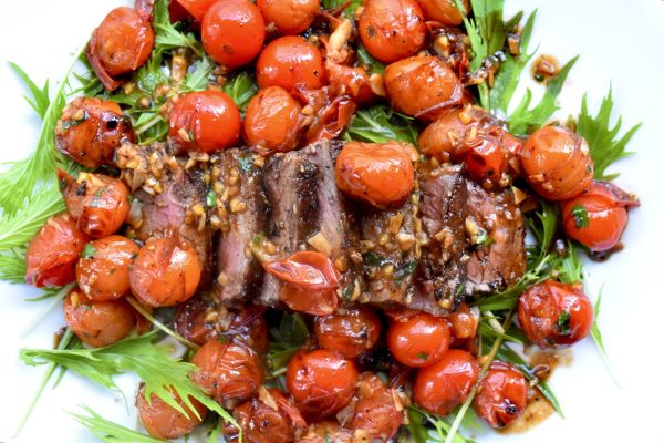 Grilled venison steak garnished with roasted cherry tomatoes.