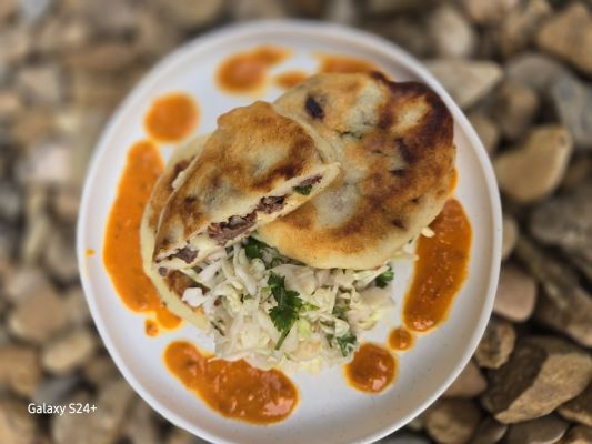Delicious pupusa served with salad and sauce on a plate.