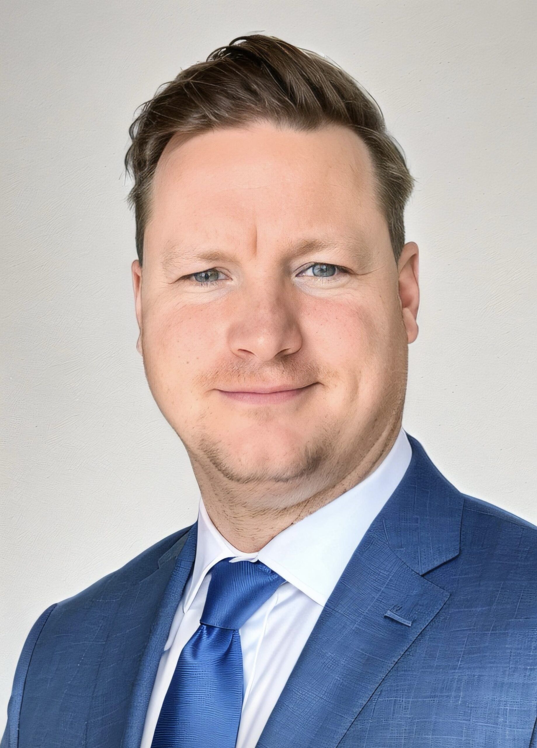 Professional headshot in business attire with blue suit and tie.