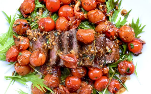 Grilled venison steak garnished with roasted cherry tomatoes.