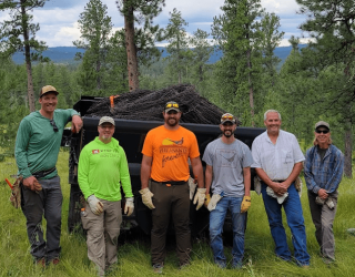Group photo of volunteers engaged in conservation work in a forested area.