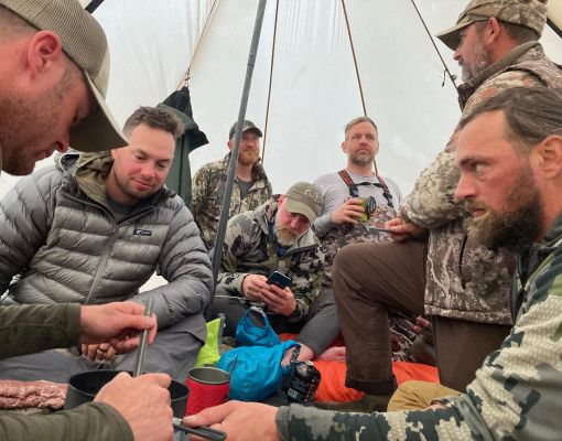 Group of hunters gathering in a tent during a hunting camp.