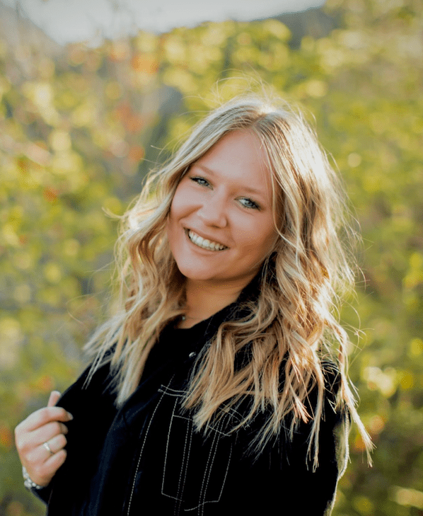 Smiling woman posing outdoors in a natural setting.