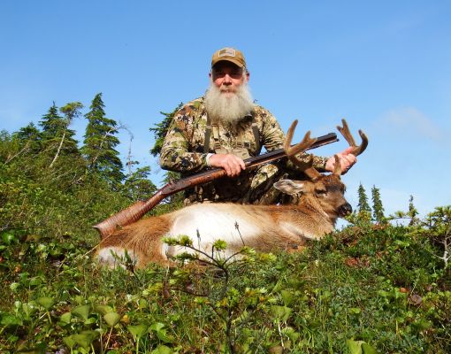 Hunter with mule deer buck in a forest setting
