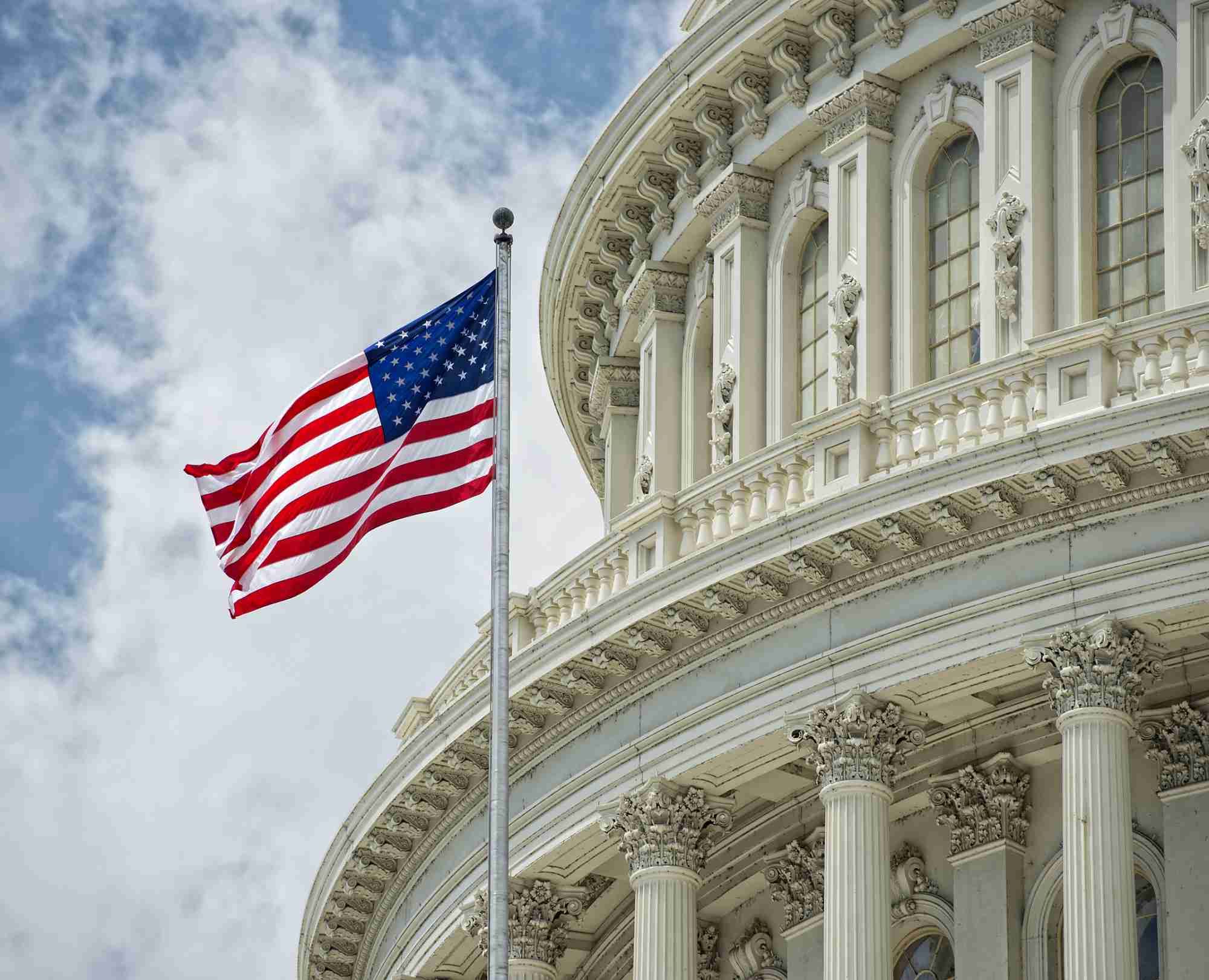 U.S. Capitol building with flag against a blue sky.