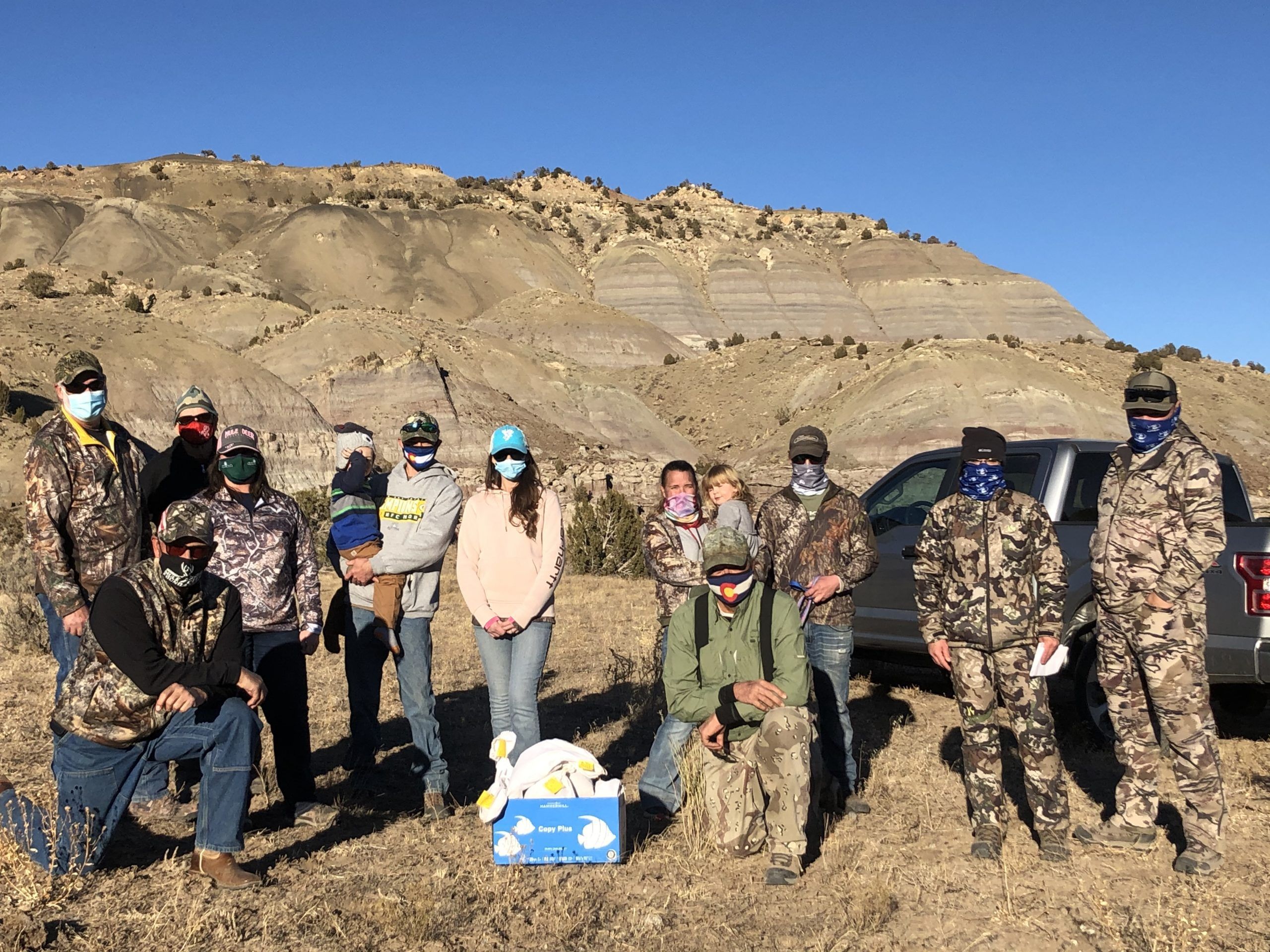 Group of volunteers in camouflage gear in a mountain setting.