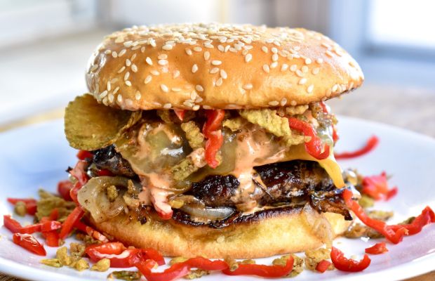 Gourmet burger with various toppings on a plate.