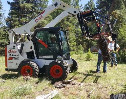 Volunteers using a Bobcat for habitat restoration.