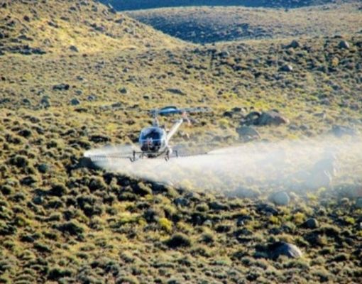 Helicopter applying spray over a mountainous area.
