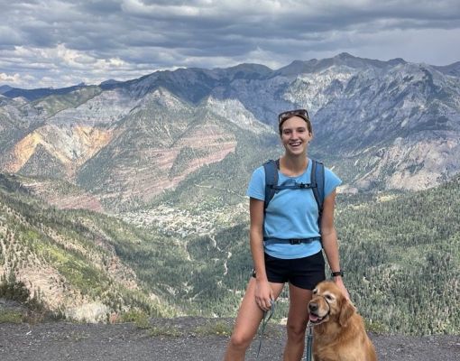 Hiker with a golden retriever enjoying a mountain view.