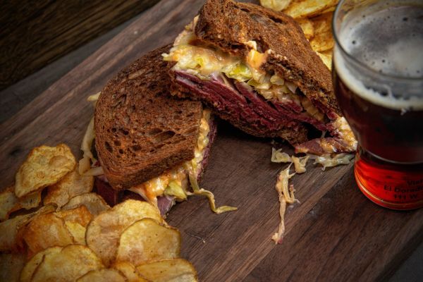 Close-up of corned beef sandwich with chips and beer