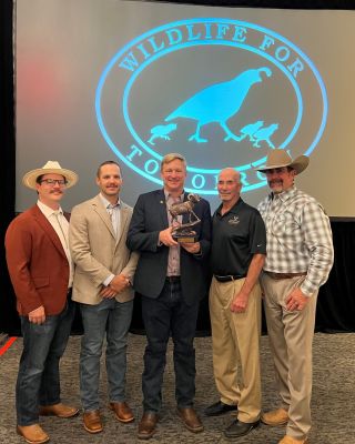 Men at a wildlife fundraising event posing with an award.