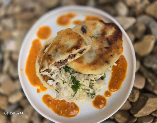 Delicious pupusa served with salad and sauce on a plate.