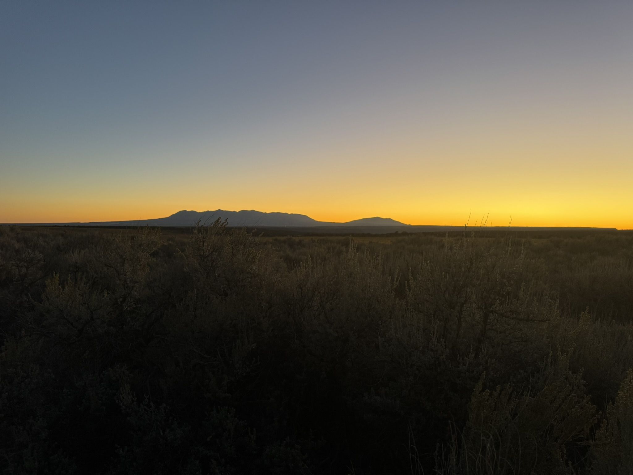 Prairie landscape at sunset with foothills in the distance.