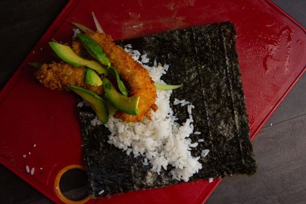 Ingredients for sushi roll including rice and avocado on nori