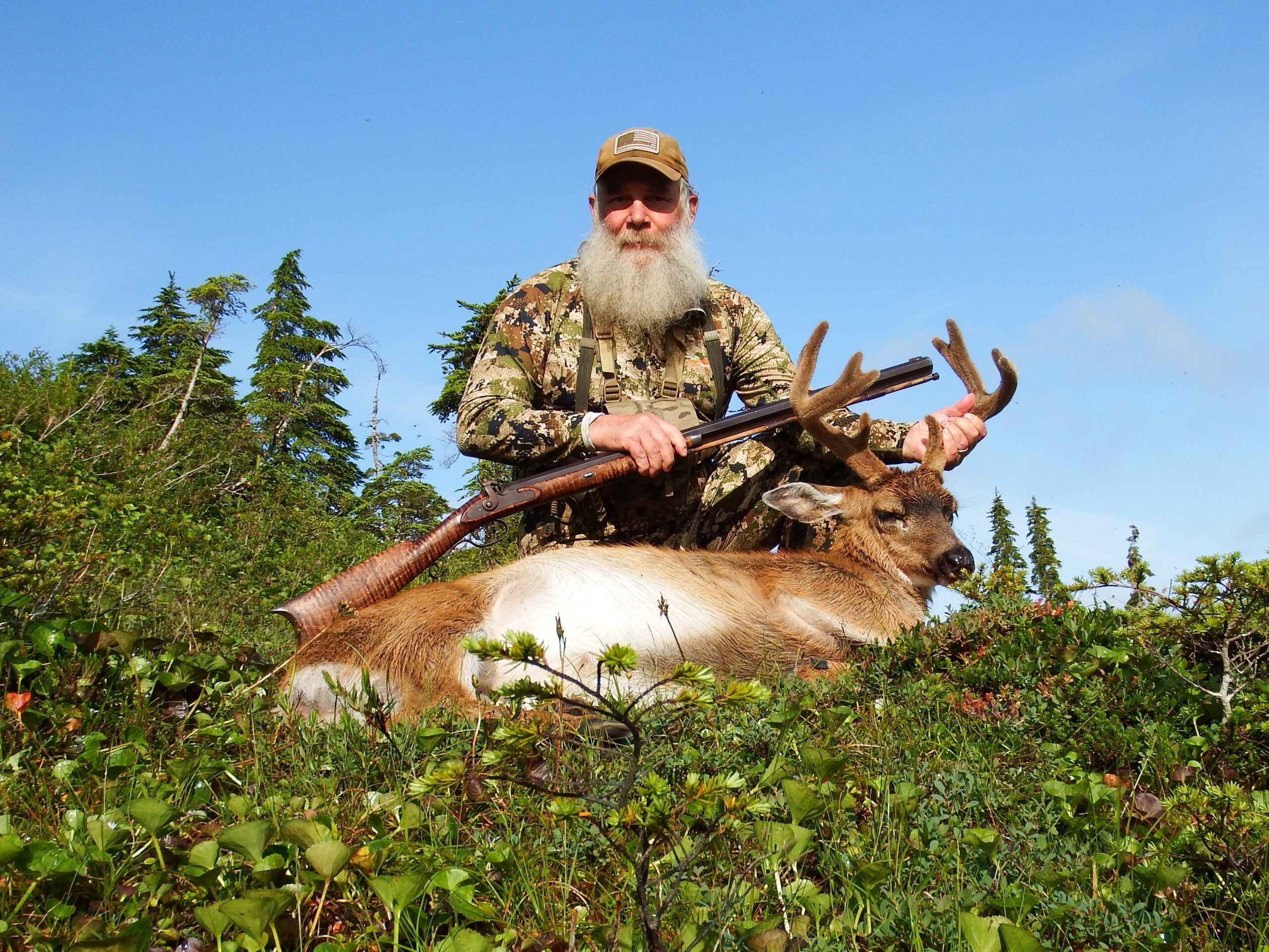 Hunter with mule deer buck in a forest setting
