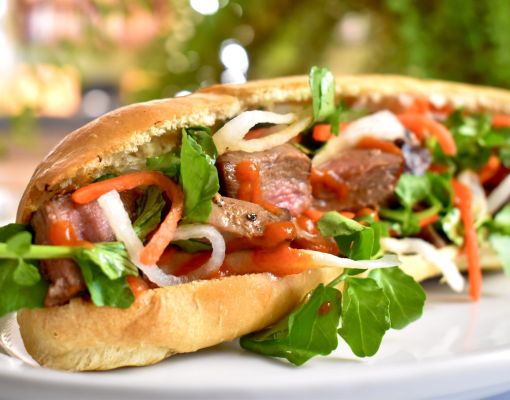 Delicious venison sandwich layered with fresh greens and sauce.