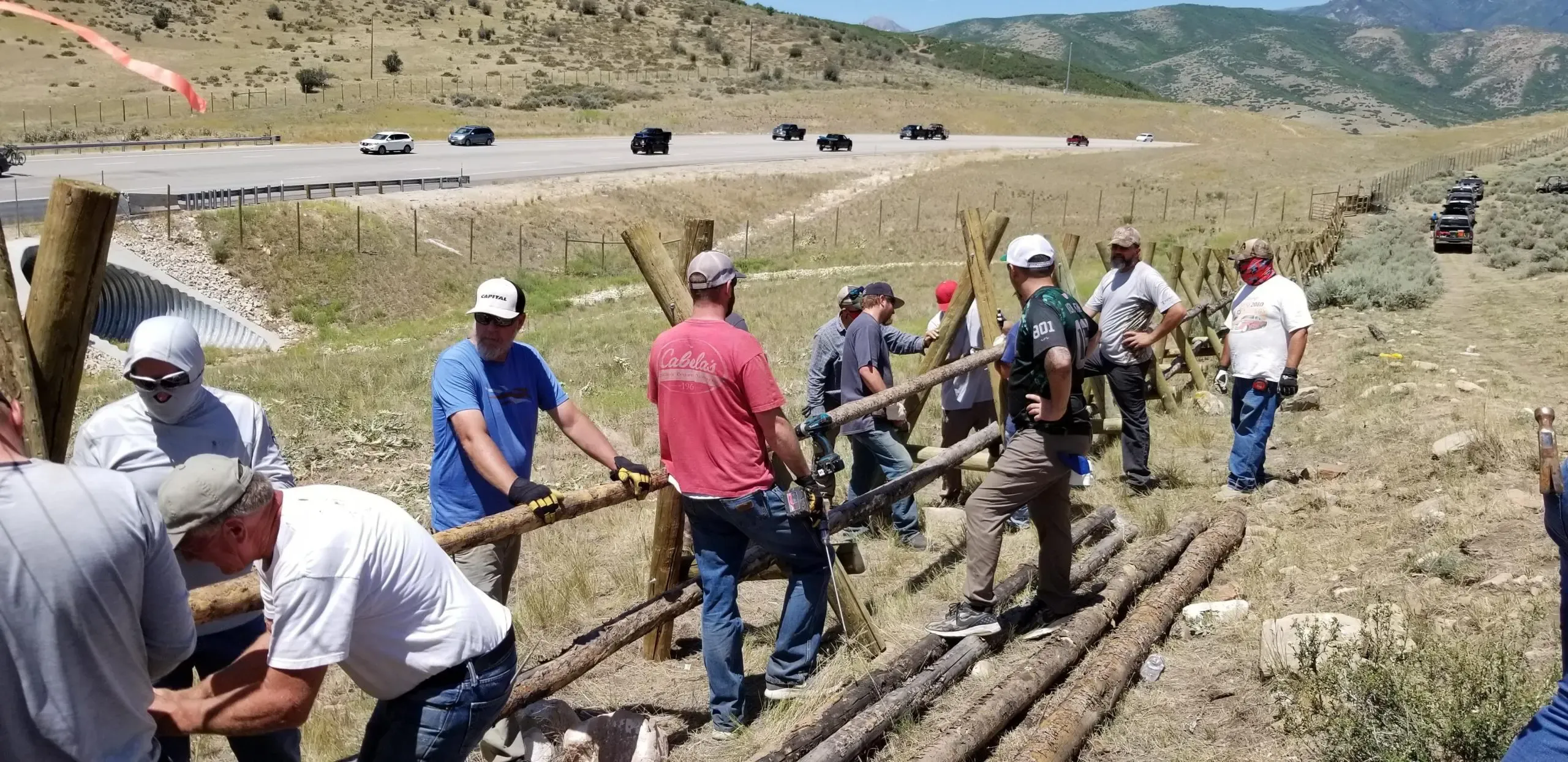 Group of volunteers constructing a fence along a highway.