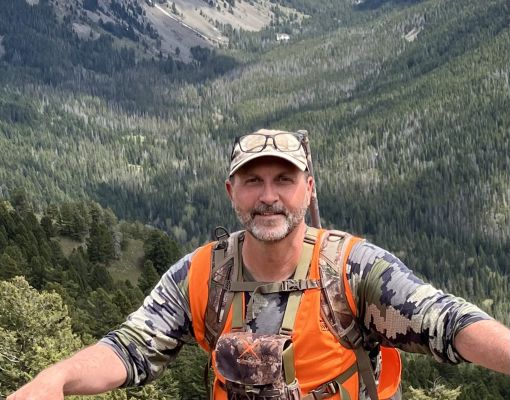 Hunter in camouflage with orange vest in the mountains
