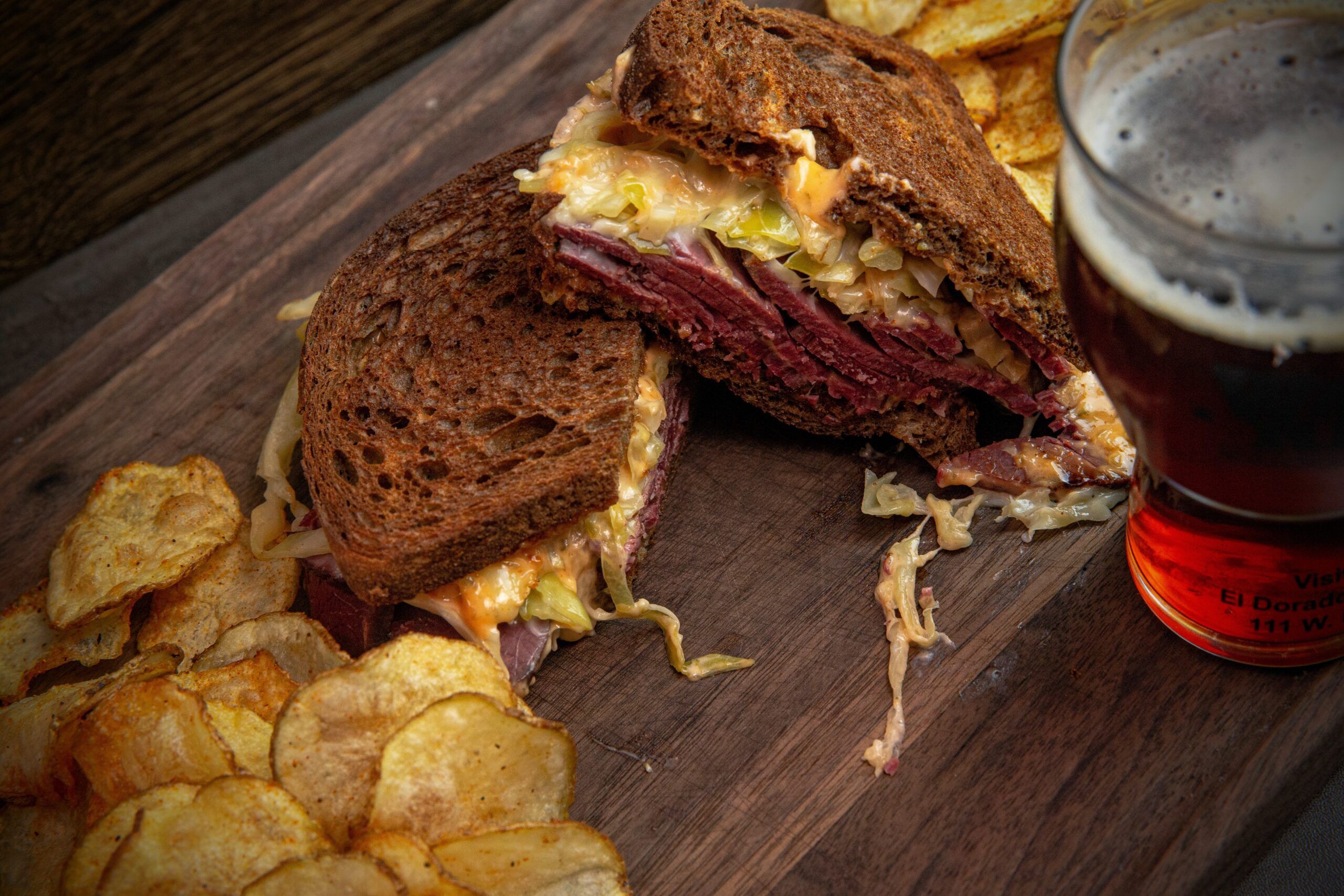Close-up of corned beef sandwich with chips and beer