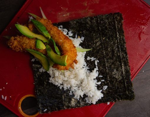 Ingredients for sushi roll including rice and avocado on nori