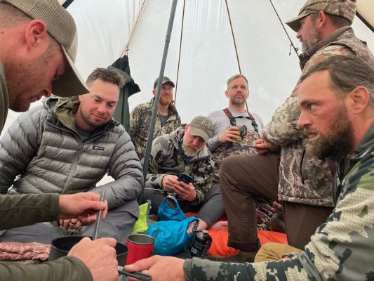Group of hunters gathering in a tent during a hunting camp.