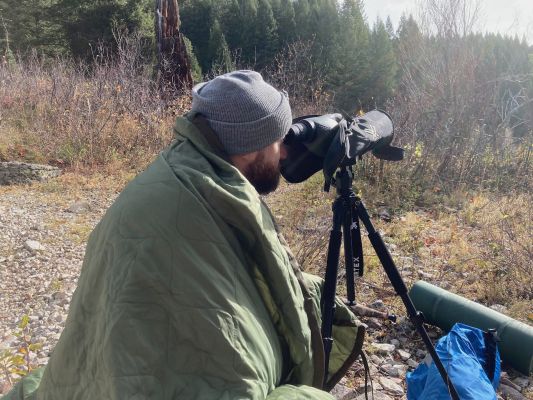 Man using spotting scope in the forest.