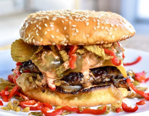 Gourmet burger with various toppings on a plate.