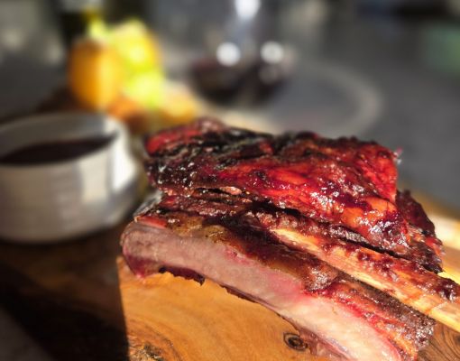 Delicious smoked ribs presented on a wooden board with sides.