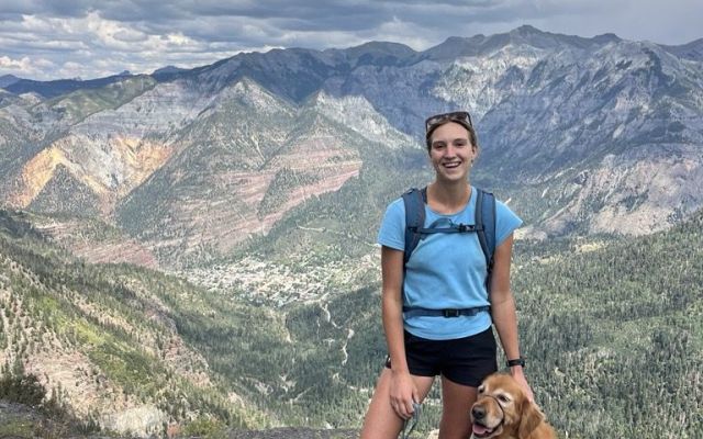 Hiker with a golden retriever enjoying a mountain view.