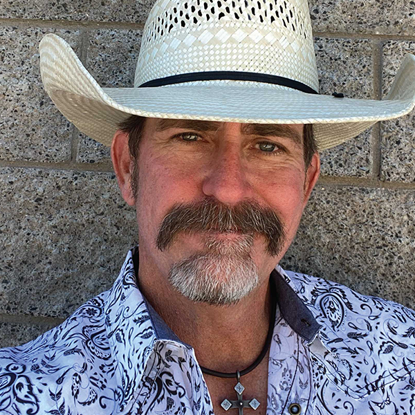 Portrait of a man wearing a cowboy hat and patterned shirt.
