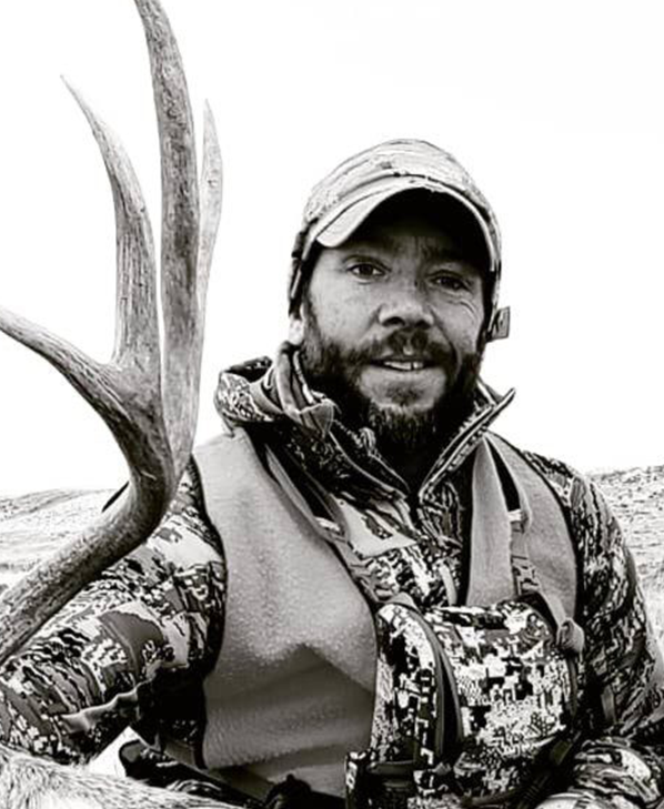 Hunter holding mule deer antlers in rugged wilderness setting