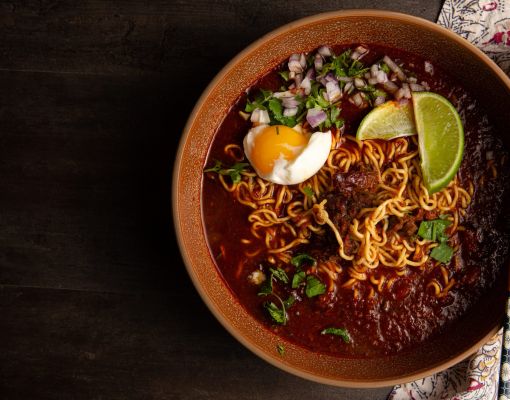 Bowl of ramen with egg, lime, and herbs