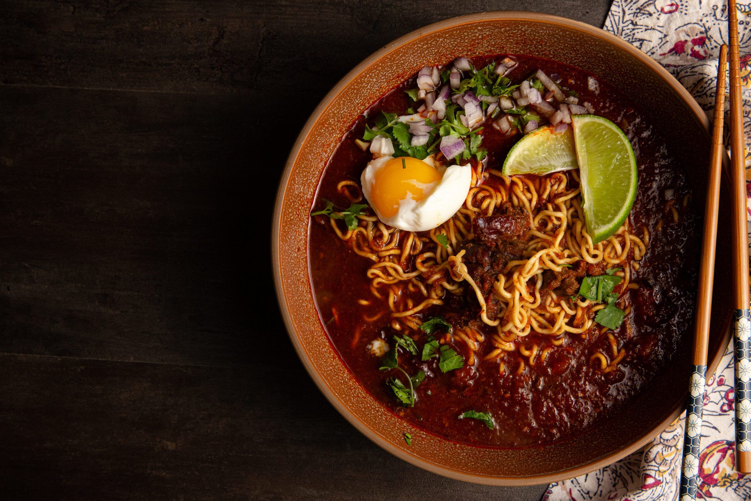 Bowl of ramen with egg, lime, and herbs