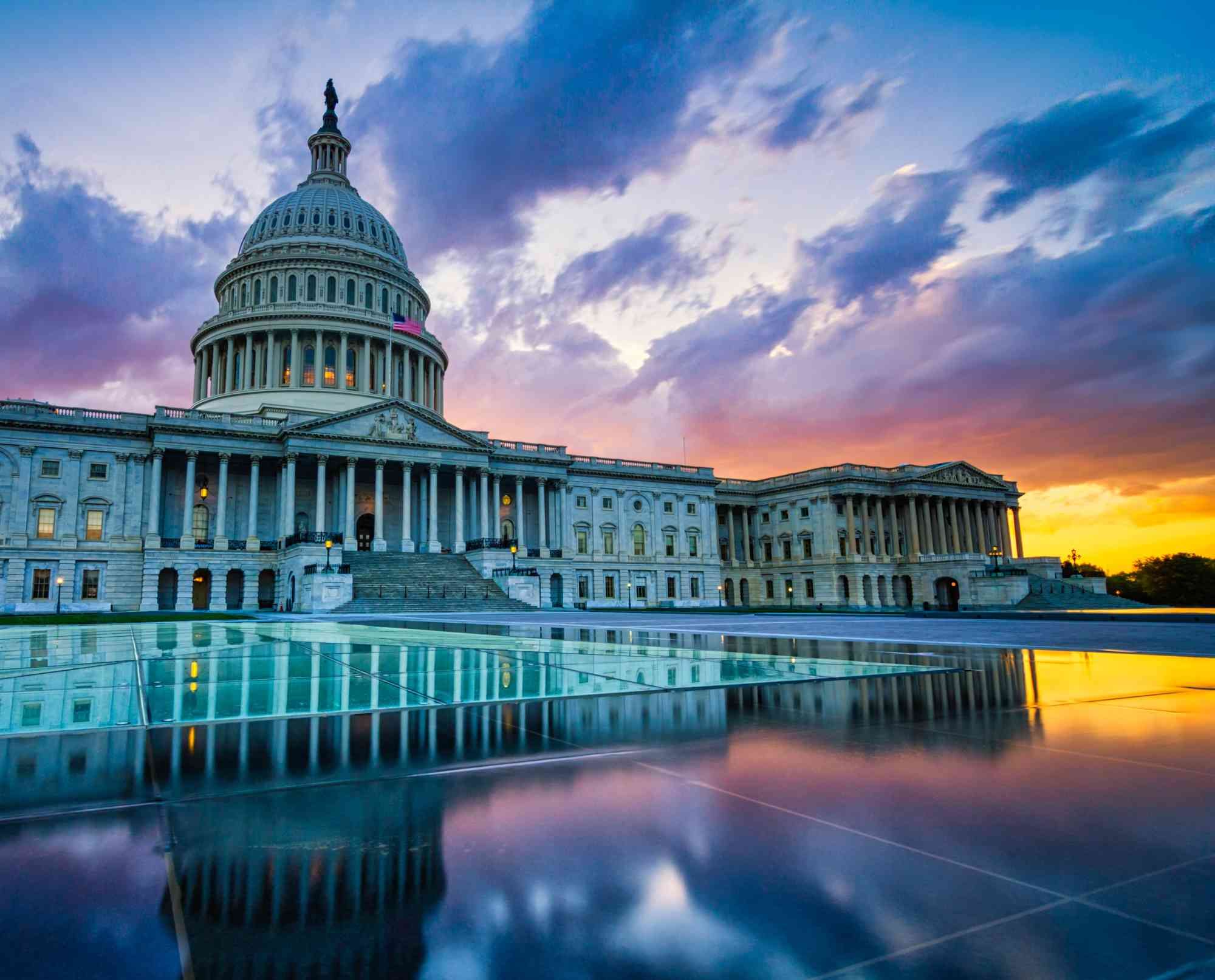 Sunset view of the US Capitol building with reflections in the foreground.