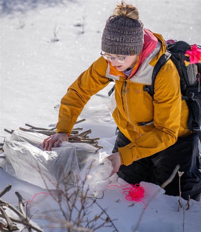 Hunter in a grassy field with a backpack and hat