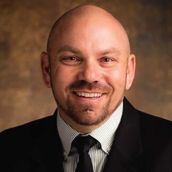 Professional headshot of a man in a suit smiling