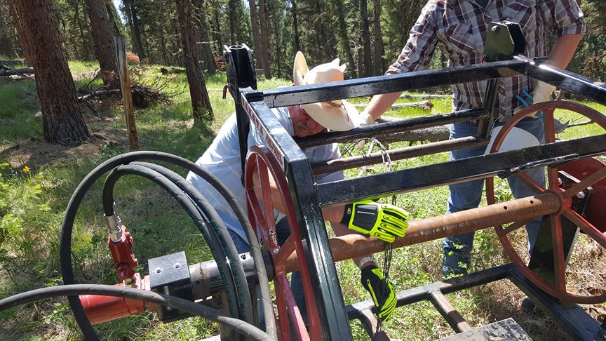 Volunteers repairing equipment in a forest setting.