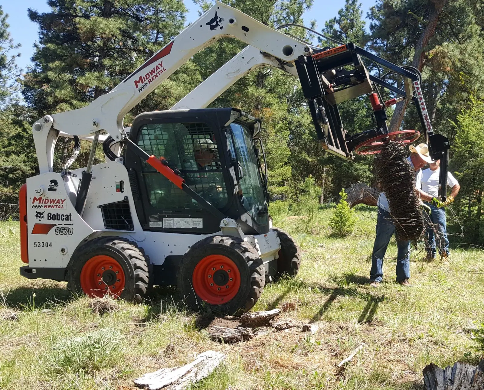 Bobcat clearing debris in forested area.