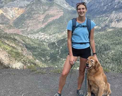 Hiker with a golden retriever enjoying a mountain view.