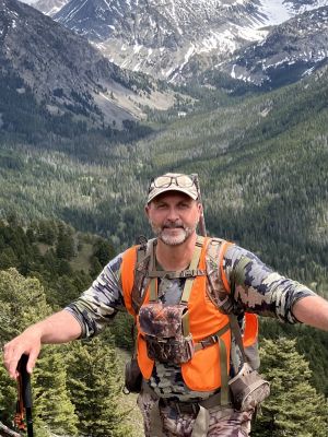Hunter in camouflage with orange vest in the mountains