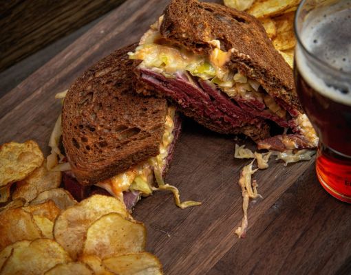 Close-up of corned beef sandwich with chips and beer