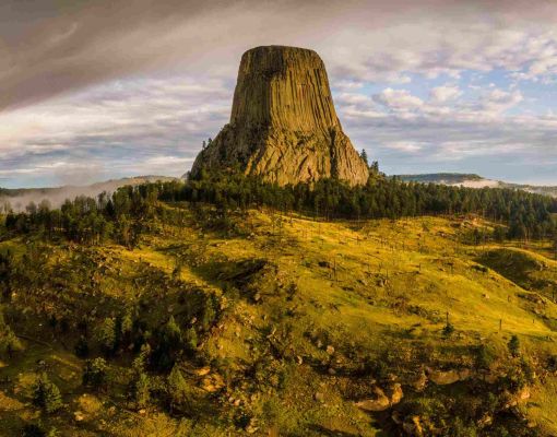 Devils Tower National Monument surrounded by forest and grasslands.