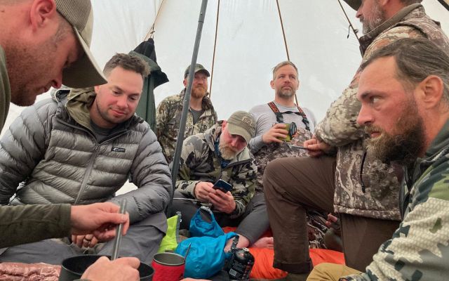 Group of hunters gathering in a tent during a hunting camp.