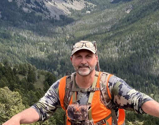 Hunter in camouflage with orange vest in the mountains