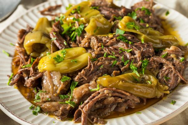 Pulled venison served with peppers and herbs on a plate.