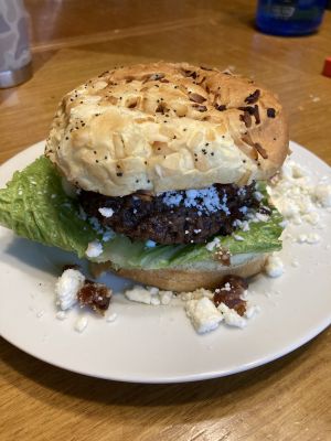 Burger with lettuce, cheese, and an onion bun on a plate.