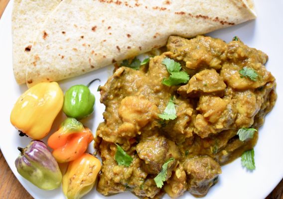 Cooked meat with colorful peppers and flatbread on a plate.