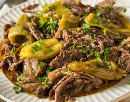 Pulled venison served with peppers and herbs on a plate.