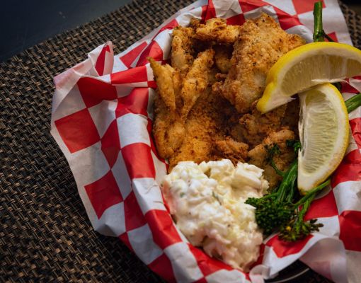 Plate of fried fish with coleslaw and lemon slices